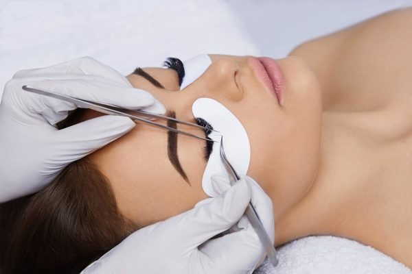 Eyelashes extensions. Fake Eyelashes. Eyelash Extension Procedure. Professional stylist lengthening female lashes. Master and a client in a beauty salon.